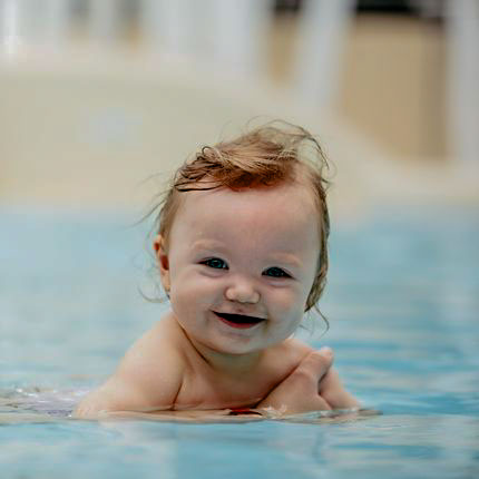 Bébé souriant qui se baigne dans la pateaugoire du camping avec piscine en bourgogne