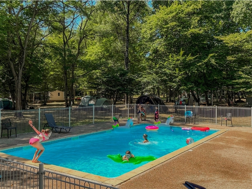 jeune fille qui saute dans l'eau de la piscine du camping en bourgogne