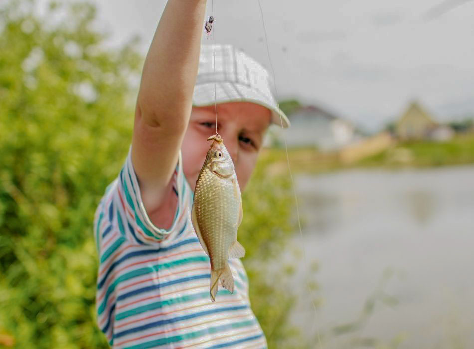 jeune garçon montrant un poisson qu'il vient de pecher au camping pas cher en bourgogne