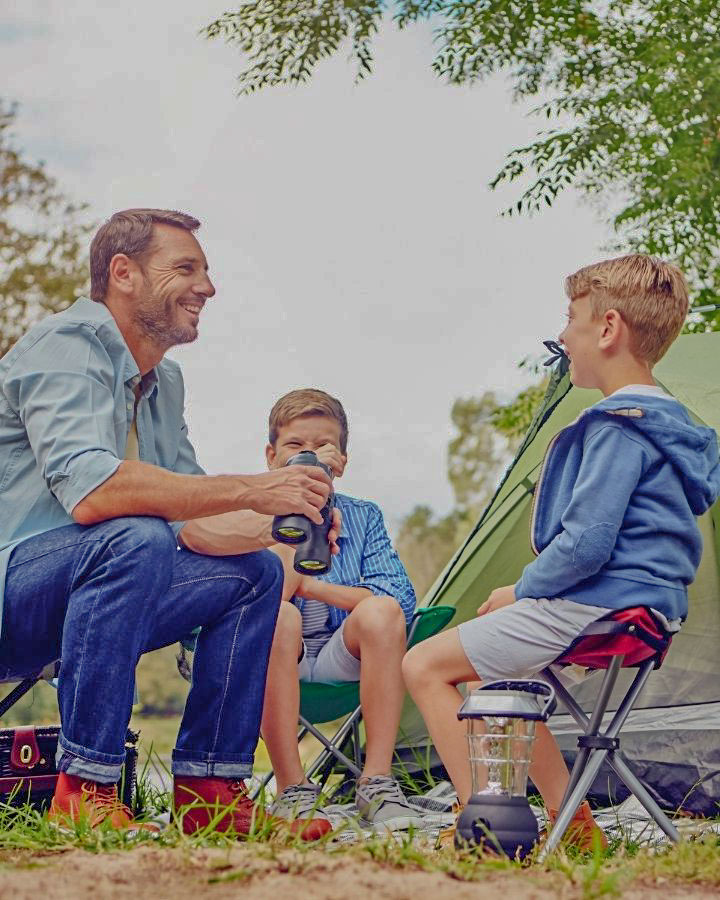 un papa et ses deux enfants en train de rigoler assis aux abord de leur tente dans le camping pas cher près de Nevers
