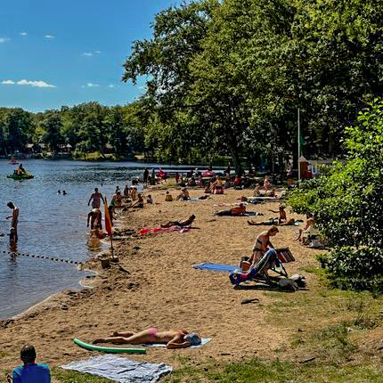 vacanciers qui profitent du soleil sur la plage et dans l'eau de la base de loisirs au camping en bord d'étang près de nevers
