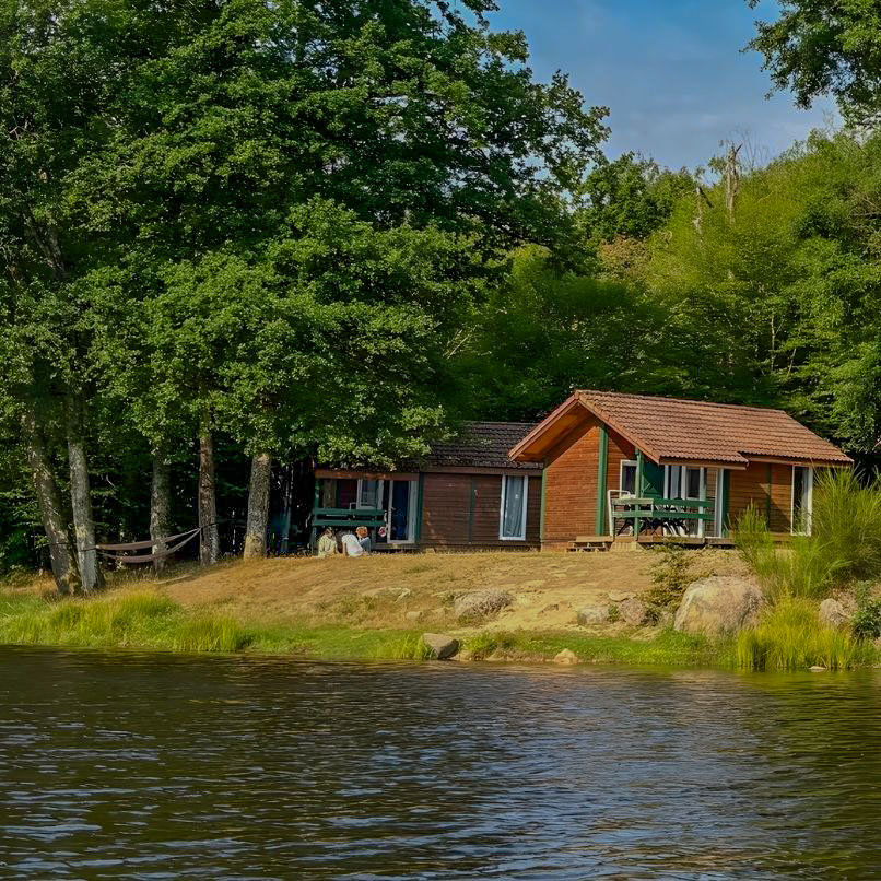vue d'un chalet en bois au bod de l'eau au camping l'étang du merle